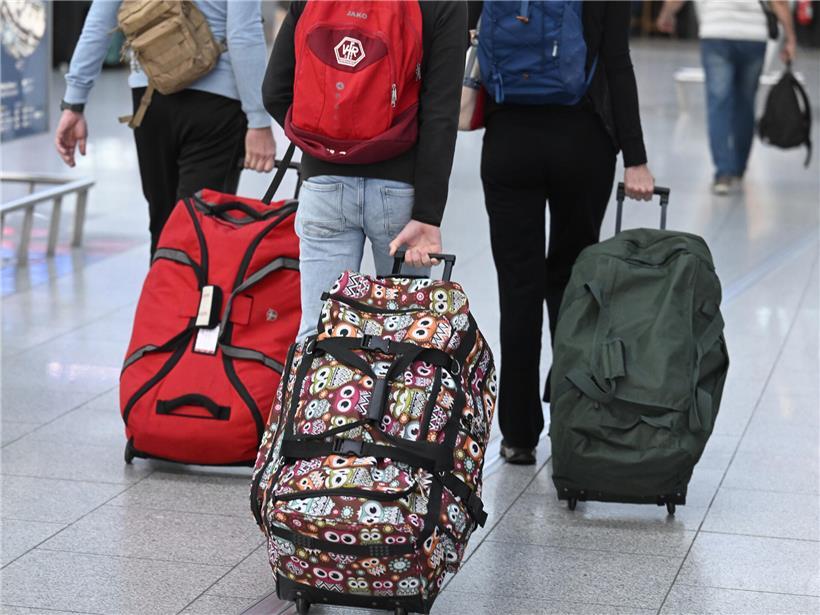 Reisende schieben Koffer in der Abflughalle des Flughafens zur Gepäckaufgabe beim Check-in