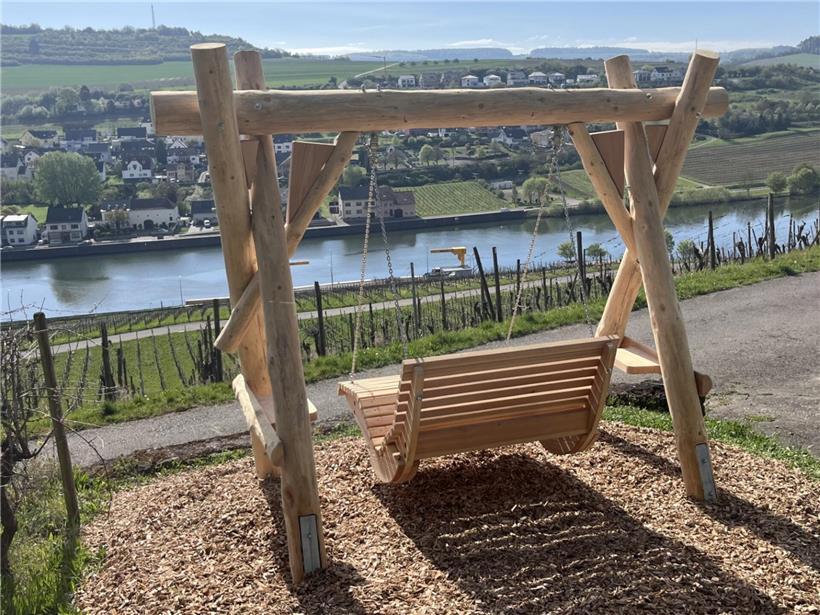 Kind schaukelt auf Holzschaukel mit grüner Landschaft und weitem Ausblick bei klarem Himmel