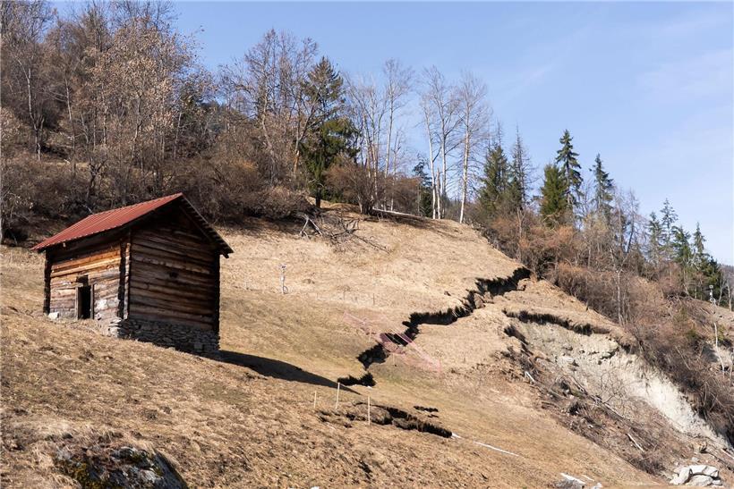 Erdabrutsch bedroht Dorfhäuser an Hang, Gefahr durch instabiles Erdreich bei Naturgefahr