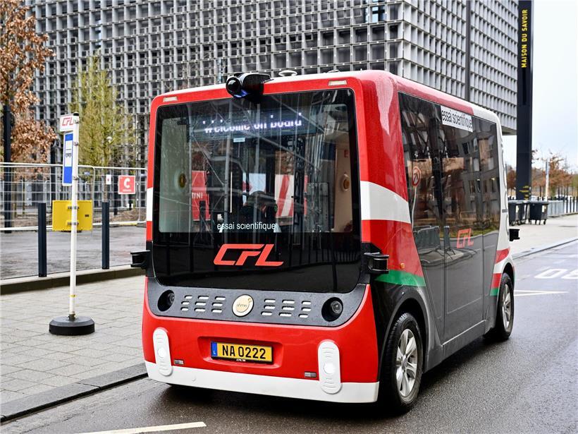 Shuttles mit Aufschrift „essai scientifique“ an Haltestelle, Passagiere steigen trotz Hinweis ein