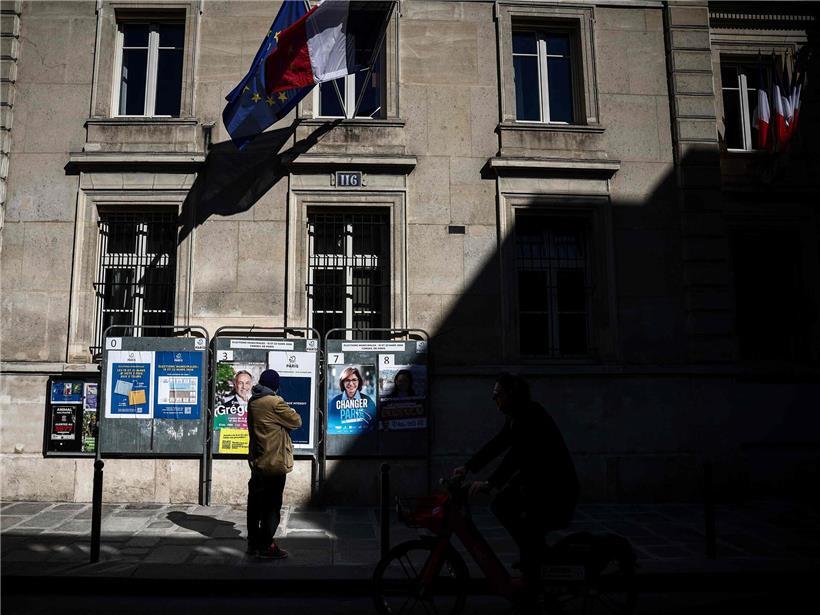 Person betrachtet Wahlplakate der letzten drei Pariser Bürgermeisterkandidaten während der Kommunalwahl