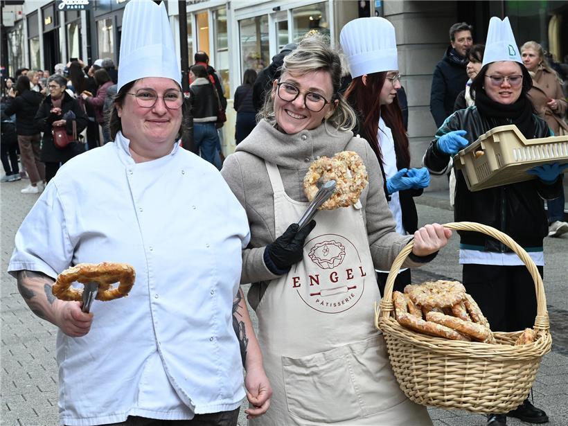 Verteilung von frischem Gebäck in belebter Fußgängerzone bei sonnigem Wetter