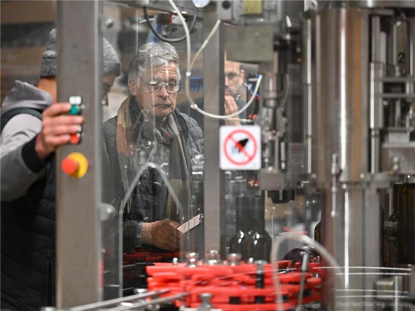 Winzer Laurent und Kellermeister Marc überwachen konzentriert die moderne Weinabfüllanlage im Weinkeller