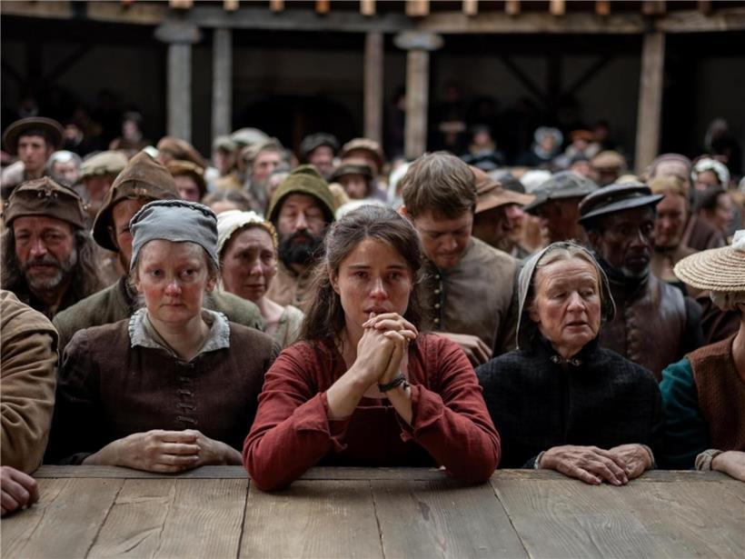 Jessie Buckley als Agnes, Shakespeares Ehefrau, zentrale Figur im Theaterstück Hamnet, Bühnenbild im Hintergrund