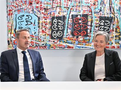 Xavier Bettel und Paulette Lenert im politischen Konflikt während Corona, symbolisch getrennt und distanziert dargestellt.